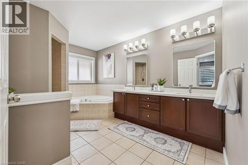 Dual sink vanity with dark wood-finish cabinetry, a large soaking tub, separate shower, and tiled flooring - 154 Falconridge Drive, Kitchener, ON 