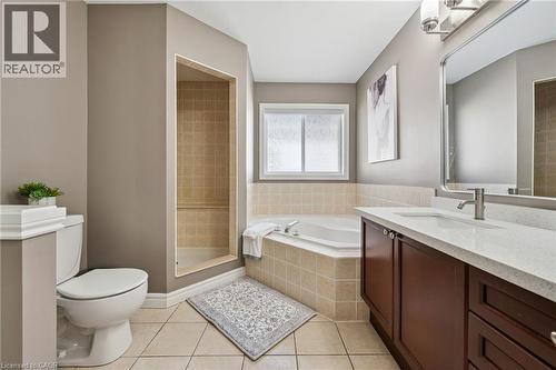 Tiled flooring, built-in shower stall with tiled walls, soaking tub with tiled surround, single vanity with light-tone countertop, and a window for natural light - 154 Falconridge Drive, Kitchener, ON 