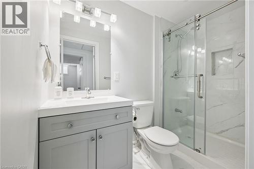 Vanity with a white countertop and gray cabinetry, mirrored medicine cabinet, and a glass-enclosed shower with a built-in niche - 154 Falconridge Drive, Kitchener, ON 