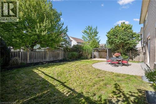 Expansive backyard featuring a circular paver patio, wood privacy fencing, mature trees, and a pergola structure - 154 Falconridge Drive, Kitchener, ON 