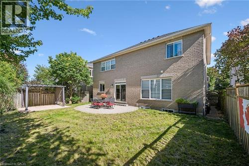 Expansive lawn with a circular paved patio, sliding glass door access, and a dedicated pergola area - 154 Falconridge Drive, Kitchener, ON 