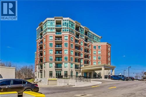 Multi-story building featuring brick and stone exterior, extensive window glazing, and individual balconies - 2750 King Street E Unit# 103, Hamilton, ON 