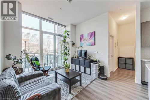 Floor-to-ceiling windows, balcony access, light wood-finish flooring, recessed lighting, and kitchen with light cabinetry - 2750 King Street E Unit# 103, Hamilton, ON 