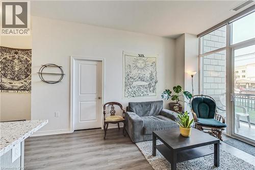 Light wood-finish flooring, white walls, and a built-in kitchen counter with a speckled surface - 2750 King Street E Unit# 103, Hamilton, ON 