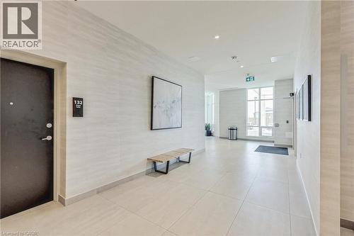 Modern corridor featuring light-toned tile flooring, recessed lighting, expansive windows, and textured wall coverings - 2750 King Street E Unit# 103, Hamilton, ON 