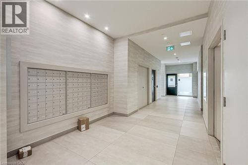 Recessed lighting illuminates the hallway with large format tile flooring and textured wall finishes - 2750 King Street E Unit# 103, Hamilton, ON 