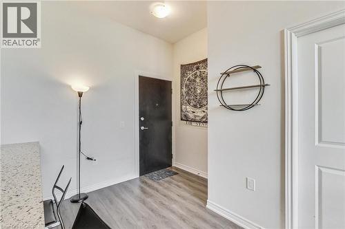 Entryway featuring wood-finish flooring, a solid panel entry door, and a built-in ceiling light fixture - 2750 King Street E Unit# 103, Hamilton, ON 