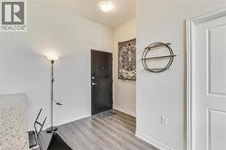 Entryway featuring wood-finish flooring, a solid panel entry door, and a built-in ceiling light fixture - 