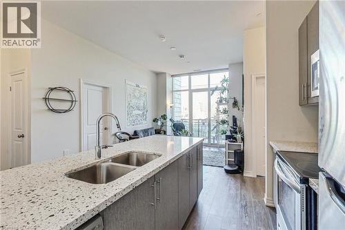 Kitchen island with dual basin stainless steel sink, gooseneck faucet, and light-toned speckled countertop - 2750 King Street E Unit# 103, Hamilton, ON 