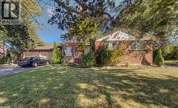 Brick exterior with white siding accents, an attached two-car garage, mature trees, and a green lawn - 