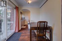 Wood-finish flooring throughout, sliding glass door with balcony access, arched entryway, and built-in kitchen cabinetry with tile backsplash - 