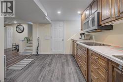 Wood-finish flooring, recessed lighting, wood cabinetry, built-in microwave, and integrated cooktop - 