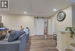 Recessed lighting, wood-finish flooring, white paneled barn door, and a white interior door - 