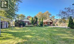 Expansive lawn area with mature trees, a brick exterior building, and a separate wood-sided structure - 