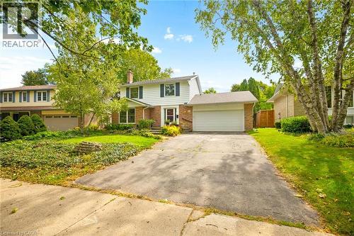 Two-story residence with white siding, brick accents, a two-car garage, and mature trees - 351 Craigleith Drive, Waterloo, ON 