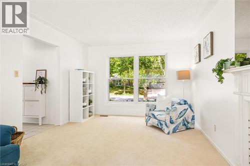 White painted walls, carpeted flooring, a large window, and a white decorative fireplace mantel - 351 Craigleith Drive, Waterloo, ON 