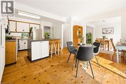 Kitchen with wood-finish flooring, white cabinetry, a central island, and stainless steel appliances - 