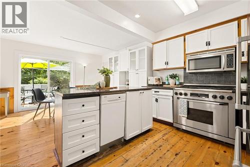 Kitchen featuring white cabinetry, stainless steel appliances, dark countertops, and wood-finish flooring - 351 Craigleith Drive, Waterloo, ON 