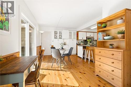 Hardwood flooring throughout, white cabinetry with glass-front uppers, and a kitchen island with seating - 351 Craigleith Drive, Waterloo, ON 