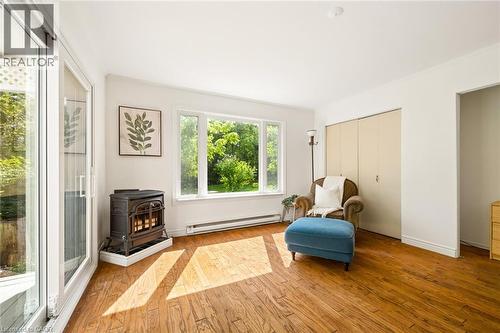 Hardwood-finish flooring, built-in wood-burning stove, white trim, sliding glass patio doors, and large picture window - 351 Craigleith Drive, Waterloo, ON 