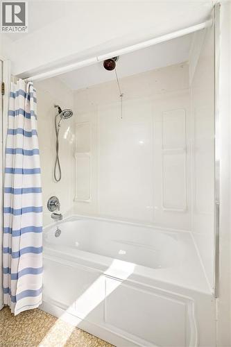 White bathtub with integrated shower, chrome fixtures, and a textured flooring - 351 Craigleith Drive, Waterloo, ON 