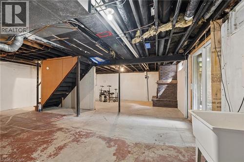 Unfinished basement with exposed ceiling joists, concrete flooring, a utility sink, and a brick-finish staircase - 351 Craigleith Drive, Waterloo, ON 