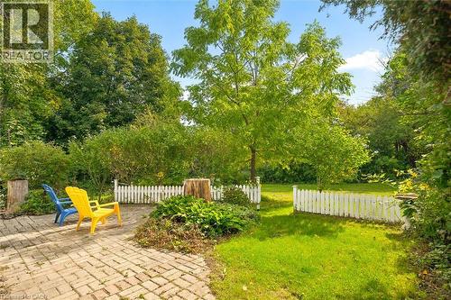 Expansive outdoor space featuring a paved patio, manicured lawn, picket fence, mature trees, and established plantings - 351 Craigleith Drive, Waterloo, ON 
