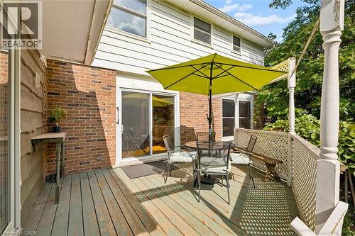 Wood-finish deck with white lattice railing, two sliding glass doors, brick exterior, and horizontal siding - 351 Craigleith Drive, Waterloo, ON 