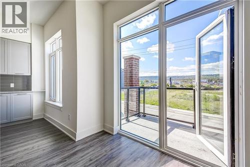 Private balcony with glass railing, expansive glass doors, wood-finish flooring, built-in cabinetry, and a subway tile backsplash - 58 Windward Drive, Grimsby, ON 