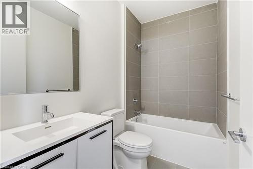 Bathroom featuring a built-in bathtub, a shower with tile surround, a vanity with an integrated sink, and a framed mirror - 58 Windward Drive, Grimsby, ON 
