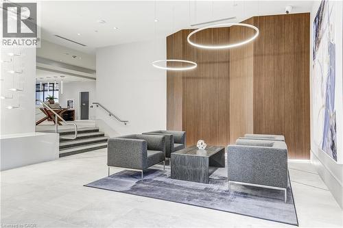 Lobby featuring wood-paneled accent wall, contemporary lighting fixtures, and a staircase with stainless steel handrails - 58 Windward Drive, Grimsby, ON 