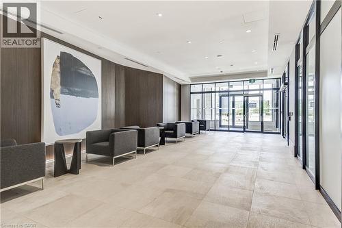 Expansive foyer featuring light-toned tile flooring, dark wood-finish wall panels, recessed lighting, and full-height glass doors - 58 Windward Drive, Grimsby, ON 