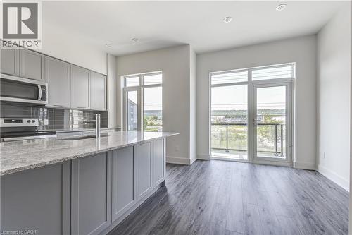 Kitchen featuring grey cabinetry, stainless steel appliances, a grey subway tile backsplash, and a large island with a light-toned countertop - 58 Windward Drive, Grimsby, ON 