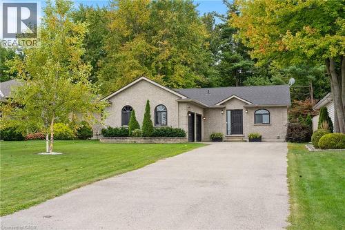 Brick facade, arched windows, attached two-car garage, mature landscaping, and an asphalt driveway - 53 Hawtrey Road, Delhi, ON 