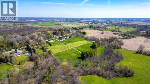 Expansive aerial showcasing a verdant landscape with agricultural fields, scattered residential properties, and a prominent river winding through the terrain - 47 River Road, Brantford, ON 