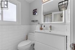 Full bathroom featuring vanity, curtained shower, tile walls, and wainscoting - 