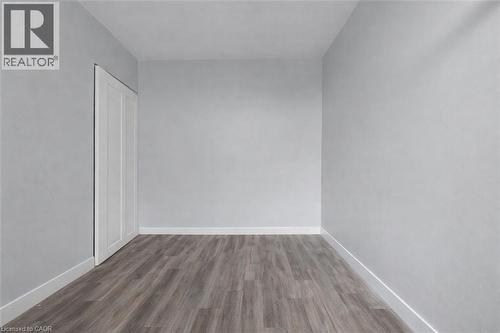 Unfurnished bedroom with dark wood-style floors and a closet - 5 Viking Court Unit# 301, Grimsby, ON 