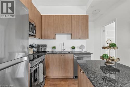 Kitchen featuring stainless steel appliances, dark stone counters, modern cabinets, light wood-style floors, and wood finish cabinetry - 460 Gordon Krantz Avenue Unit# 601, Milton, ON 
