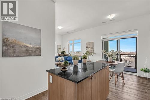 Kitchen featuring dark stone countertops, a center island, dark wood-style floors, wood finish cabinets, and modern cabinets - 460 Gordon Krantz Avenue Unit# 601, Milton, ON 