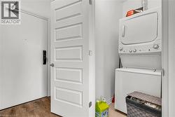 Laundry area featuring stacked washer / drying machine and light wood-type flooring - 