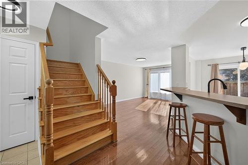 Hardwood flooring throughout, well-appointed staircase with wood banister, built-in breakfast bar, and contemporary overhead lighting - 103 Emick Drive, Ancaster, ON 
