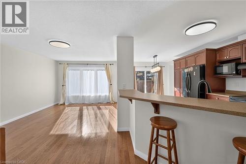 Hardwood-finish flooring, built-in kitchen cabinetry, integrated kitchen appliances, breakfast bar, and recessed lighting - 103 Emick Drive, Ancaster, ON 