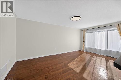 Wood-finish flooring, white baseboards, and a contemporary ceiling light fixture - 103 Emick Drive, Ancaster, ON 