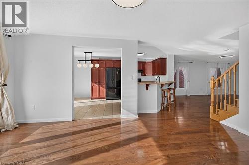 Hardwood flooring, light gray walls, built-in breakfast bar, wood cabinetry, and a wood staircase - 103 Emick Drive, Ancaster, ON 