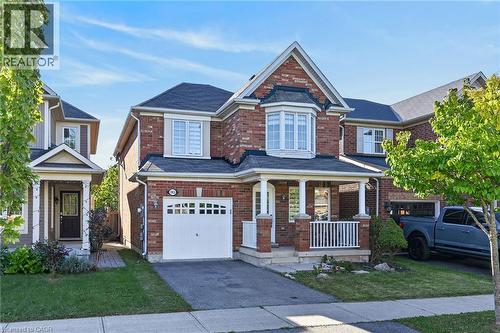 Brick exterior, covered front porch, bay window, attached garage, and paved driveway - 103 Emick Drive, Ancaster, ON 