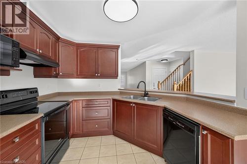 Kitchen featuring wood cabinetry, integrated appliances, a stainless steel double basin sink, and tile flooring - 103 Emick Drive, Ancaster, ON 