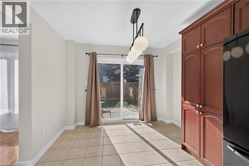 Built-in cabinetry with crown molding, tiled flooring, track lighting with globe fixtures, and a sliding glass door to the exterior patio - 103 Emick Drive, Ancaster, ON 