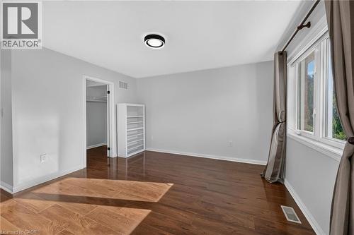 Wood-finish flooring, white trim, and a modern flush-mount light fixture - 103 Emick Drive, Ancaster, ON 