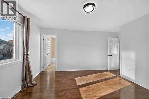 Spacious interior with wood-finish flooring, a large window, and a modern ceiling light fixture - 103 Emick Drive, Ancaster, ON 