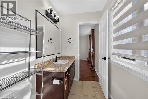 Vanity with a granite-style countertop, undermount sink, and dark wood-finish cabinetry - 103 Emick Drive, Ancaster, ON 